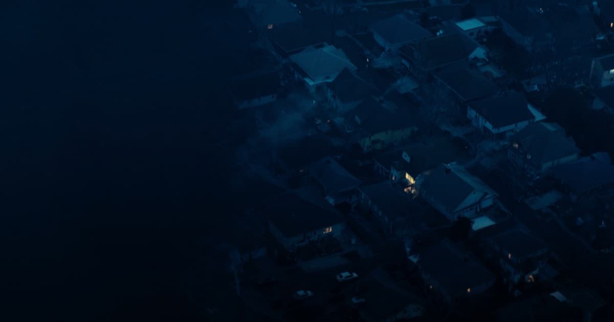 Aerial dusk view of rooftops in a landlord-friendly rental market, a handful of windows lit.